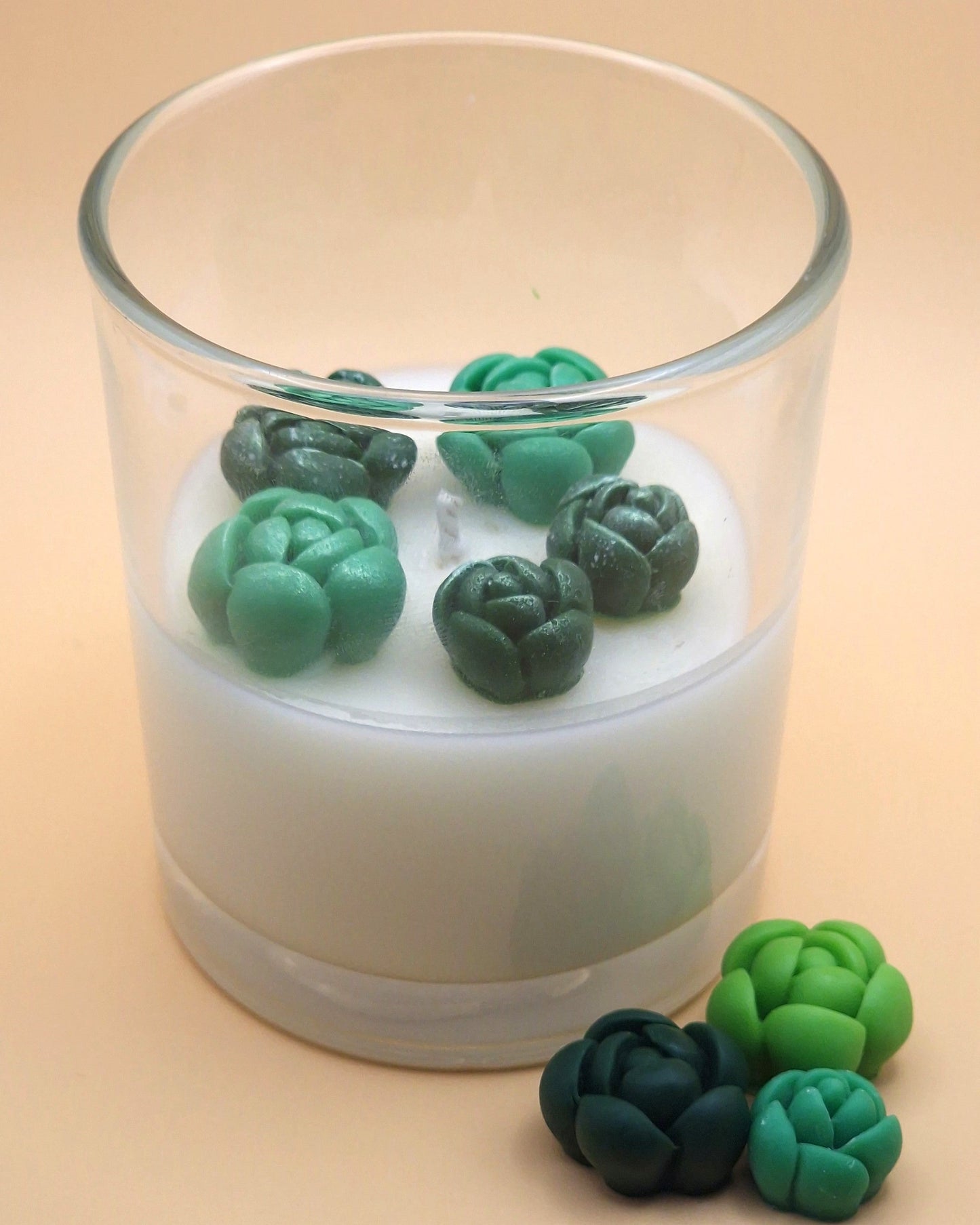 Candle with green succulent-shaped wax melts on a beige background
