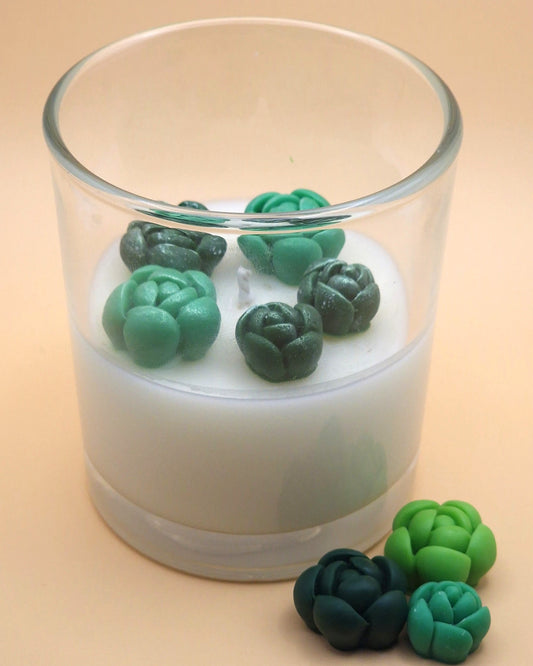 Candle with green succulent-shaped wax melts on a beige background