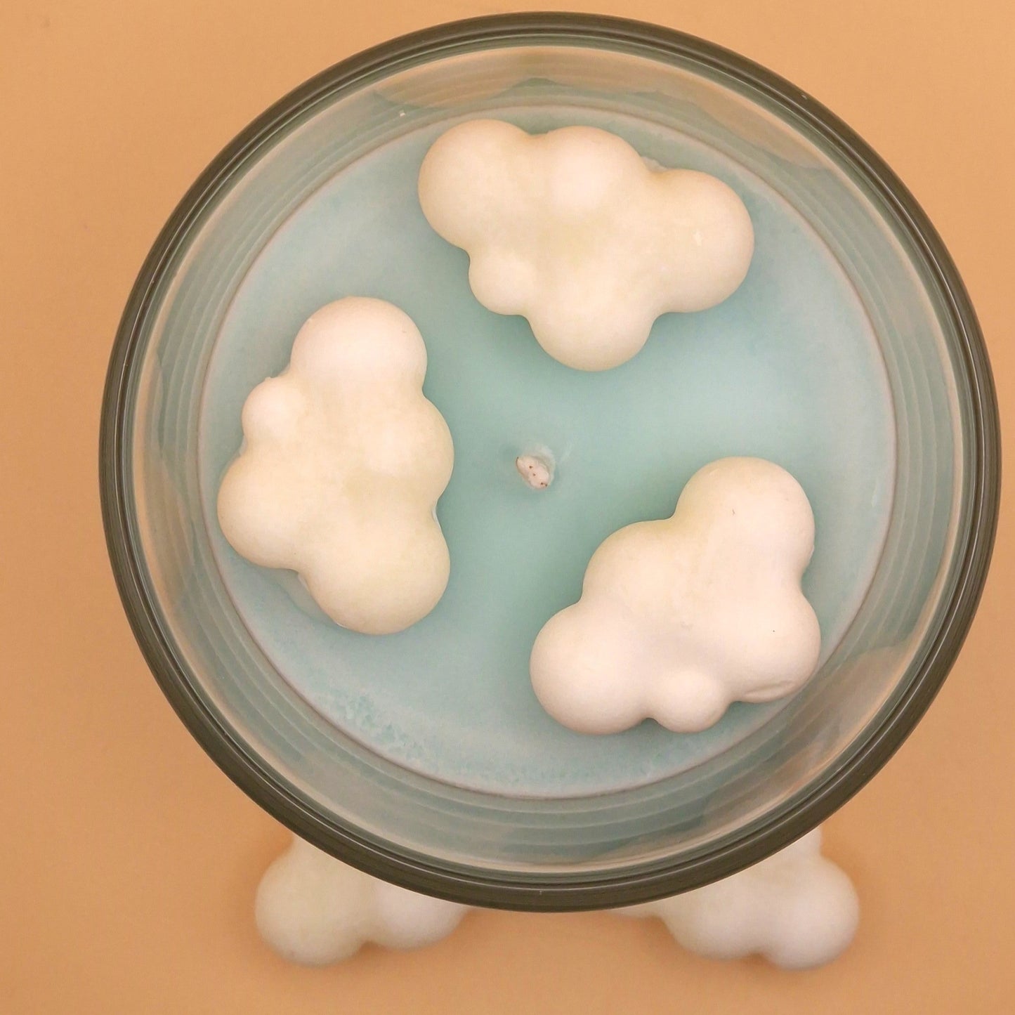 Glass container with cloud-shaped objects on a beige background