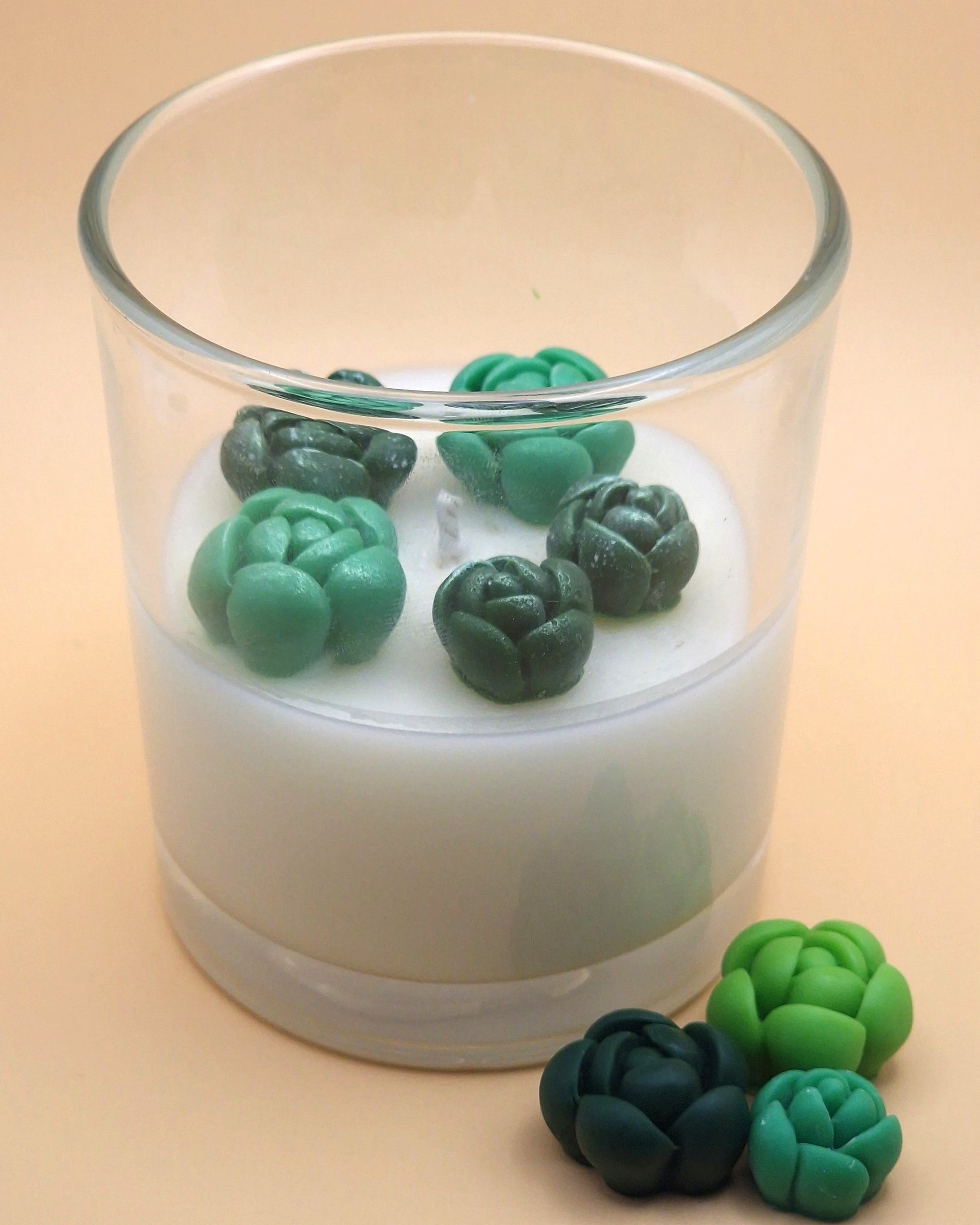 Candle with green succulent-shaped wax melts on a beige background