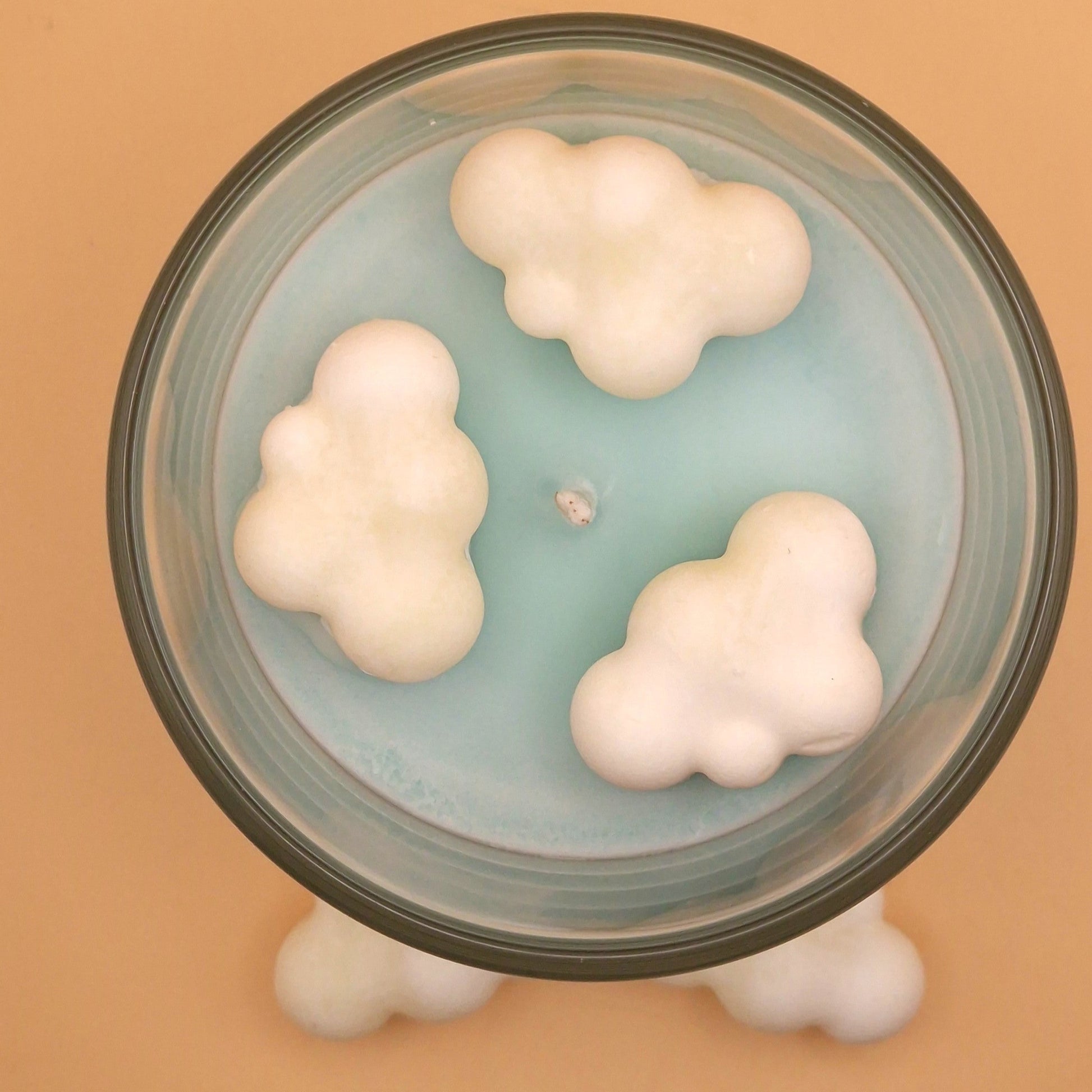 Glass container with cloud-shaped objects on a beige background