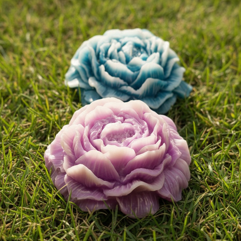 Roze en blauwe Spring Bloom wax melts in de vorm van bloemen, liggend in het gras.