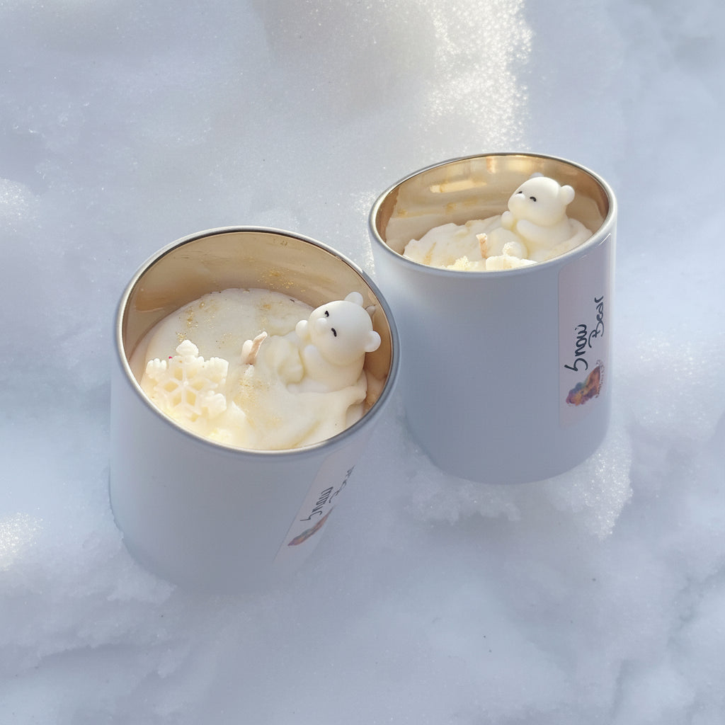 Twee Snow Bear geurkaarsen in mat witte potten met winterse decoratie.