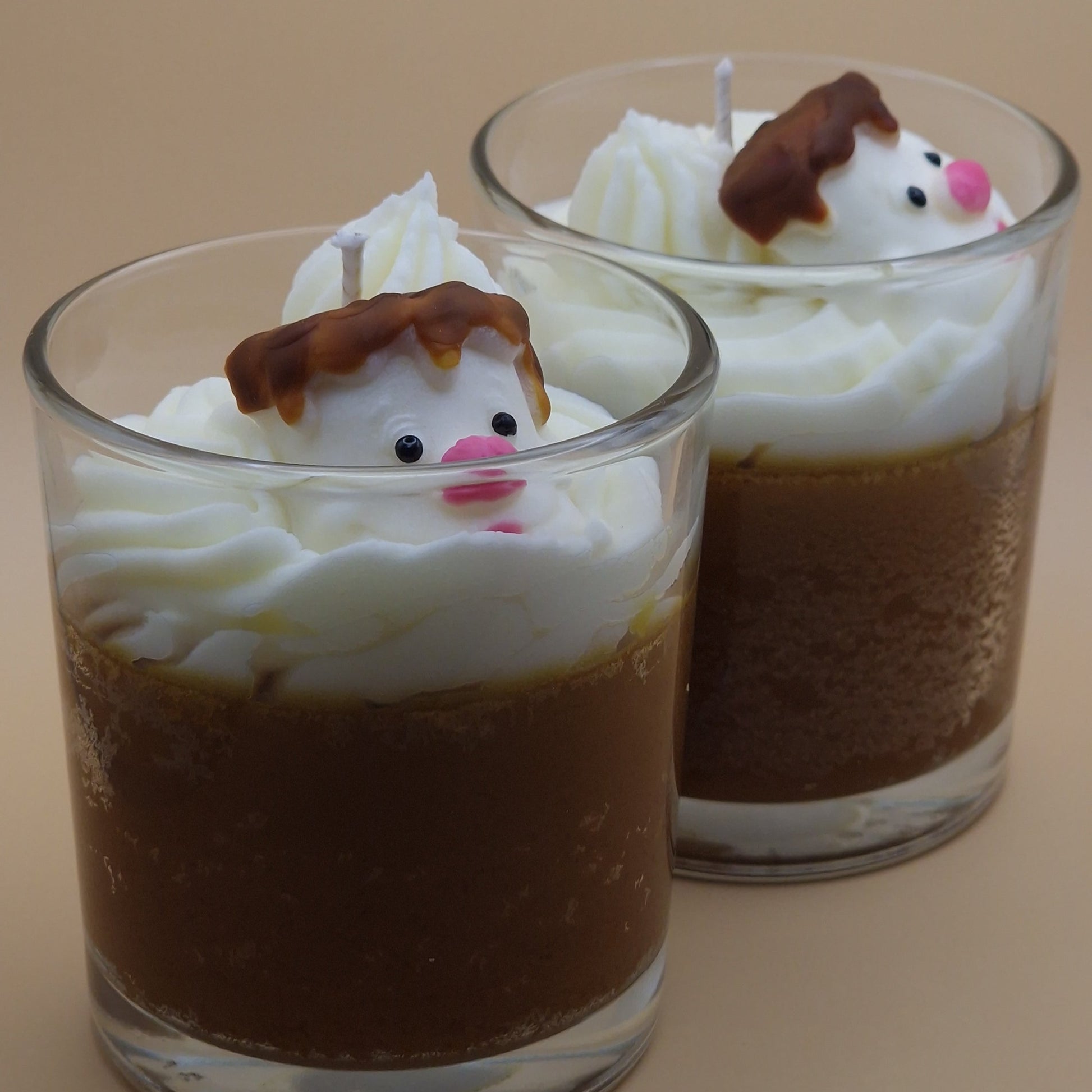 Two small glass cups with chocolate pudding and whipped cream, topped with snowman figures.